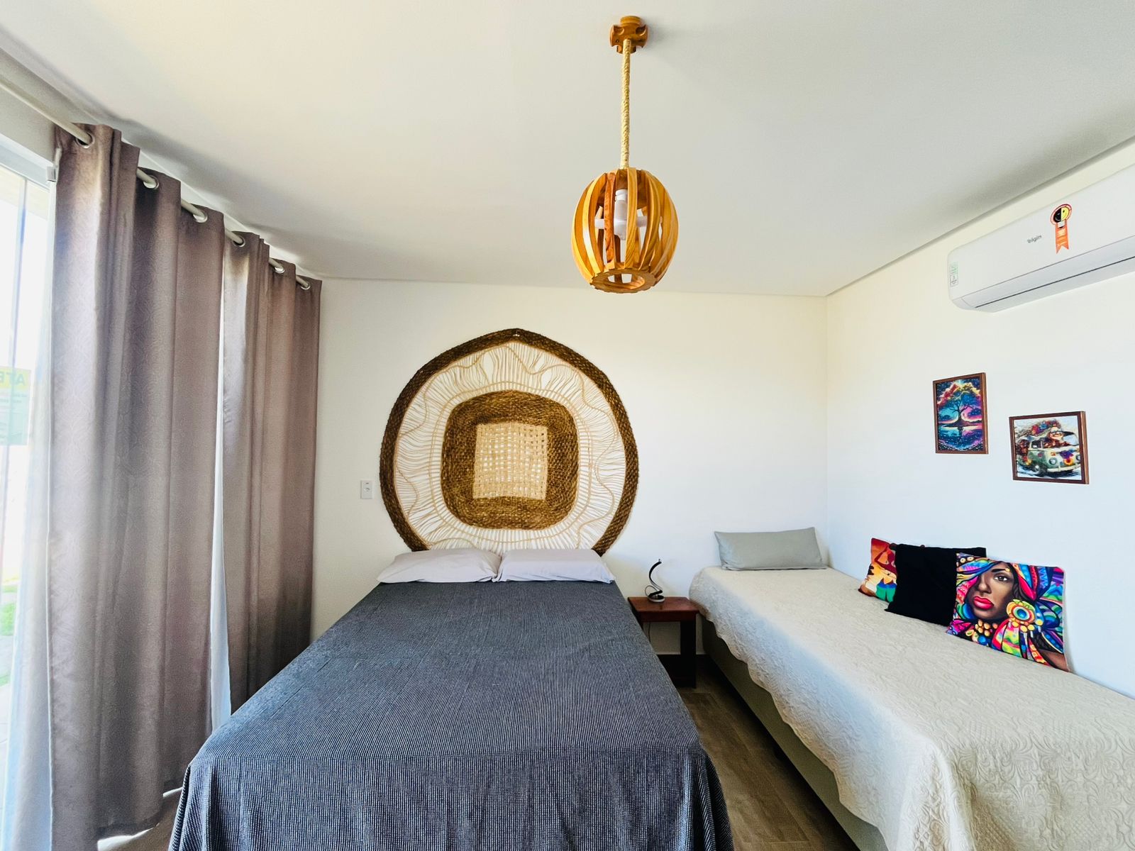 Quarto com cabeceira decorativa, cama de casal, cama auxiliar e ar-condicionado